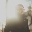 A young man walking with sun rays behind him.