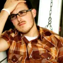 A sad looking young adult male with his hand on head.