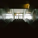 Dark stairs leading up to doors where light is coming through.