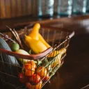 A wire shopping basket full of vegetables.