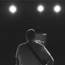 The back of a man looking at stage lights.
