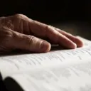 An older person's hand on a Bible.