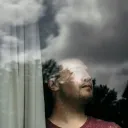 Man looking out window with gloomy clouds in the sky