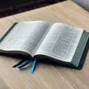an open Bible on a light-colored wood table