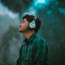 man in green and black plaid dress shirt wearing black and white headphones