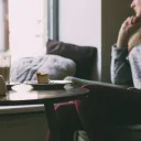 a woman seated at a table with unfinished food and looking out the window