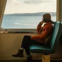 a woman sitting on a bus and looking out the window at a lake