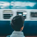 Young man facing away looking at a passing subway