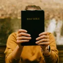 Person holding a Bible in front of their face