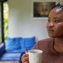 a woman holding a coffee mug and looking out the window