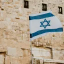 Photo of israeli flag in front of stone wall.