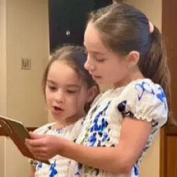 2024 Feast of Tabernacles Penang, Malaysia two girls wearing matching dresses and looking at a phone as they sing