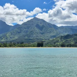 a lake with mountains and clouds in the backdrop