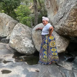 a woman leaning against a boulder