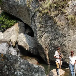 three people outdoors with rock cliffs behind them