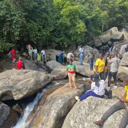 people sitting on boulders by a waterfall