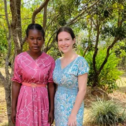 two women standing in front of a tree
