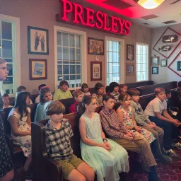 teenagers seated indoors under a sign that reads "Presley's"