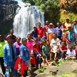 a group of people gathered in front of a waterfall