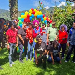 a group of people wearing party attire and standing outdoors with balloons