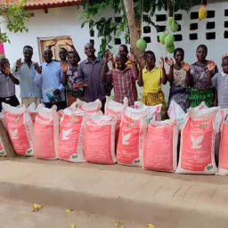 A group of brethren celebrating the delivery of farming supplies a group of people standing with bags of maize