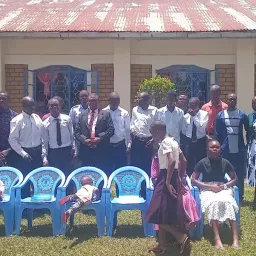 a large group of people gathered on a green lawn in front of a building