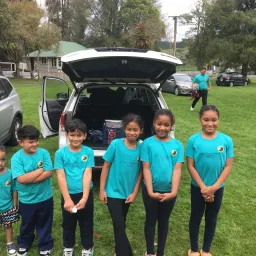 six children standing in front of a parked vehicle