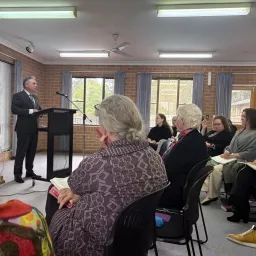 a group of women listening to a speaker at a lectern