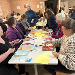 a group of women seated at a table and doing crafts