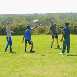 UYC British Isles children playing with a frisbee in a green field