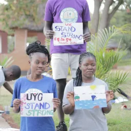 three children holding up hand-drawn signs