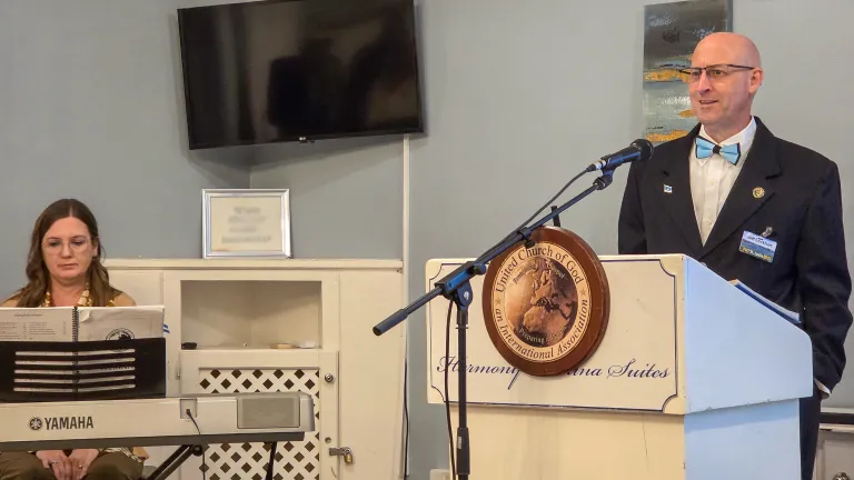a woman seated at a piano keyboard and a man standing at a lectern