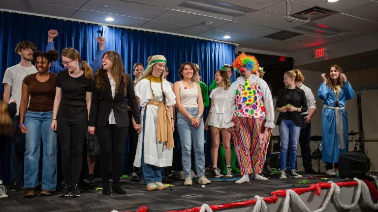 a group of young adults wearing costumes standing on a stage