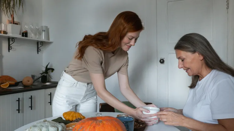 a young woman handing a bowl of soup to an older woman