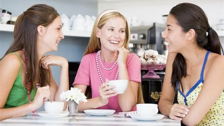 three women sitting at a table with teacups