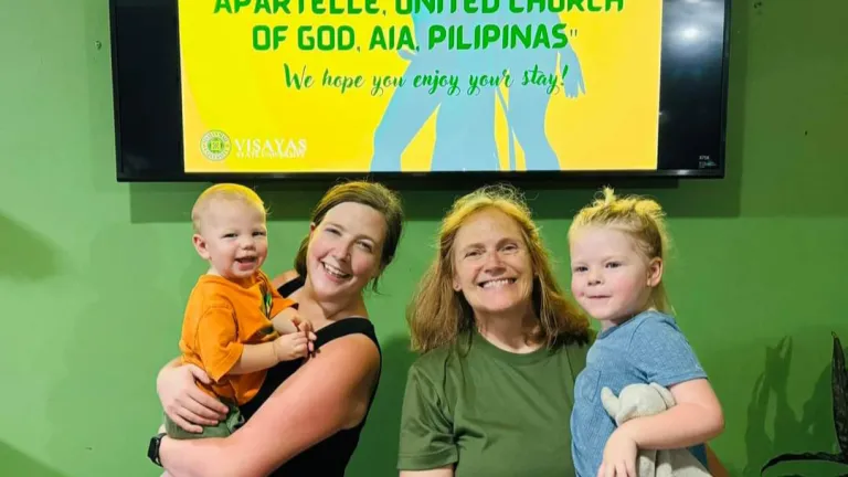 two women each holding a small child under a digital welcome sign