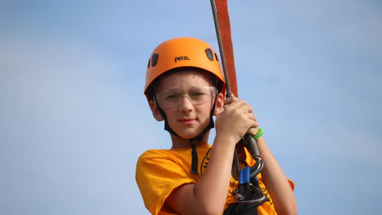 a boy swinging from a high ropes course