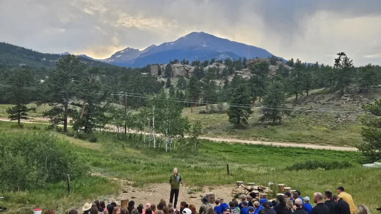 Campers gathered for campfire with a mountain range in the background