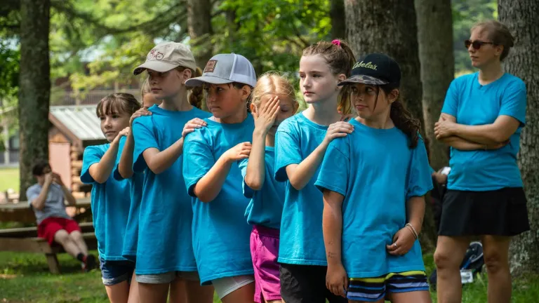 Campers with arms on camper in front of them walking in a line
