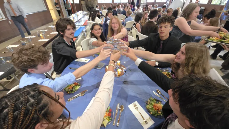 Campers at a round table clinking glasses