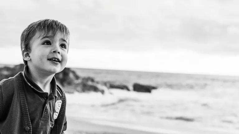 a little boy walking along the beach