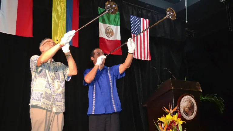 Men blowing horns against a backdrop of various countries' flags
