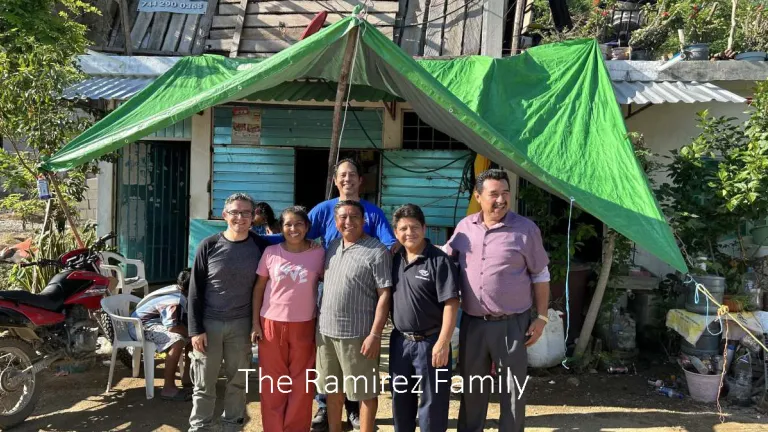 The Ramirez Family a group of people standing in front of a building with a green tarp for a roof