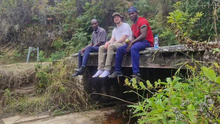 three men sitting on a bridge