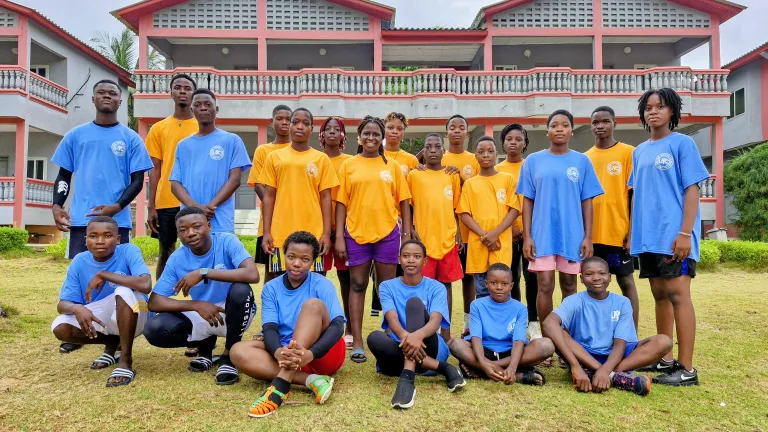 a group of teenagers standing in front of a building with pink trim