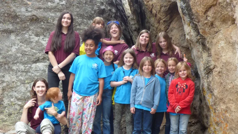 girls standing in front of a rockface with a narrow gap