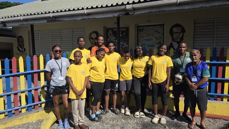 people with yellow shirts standing in front of a colorful fence