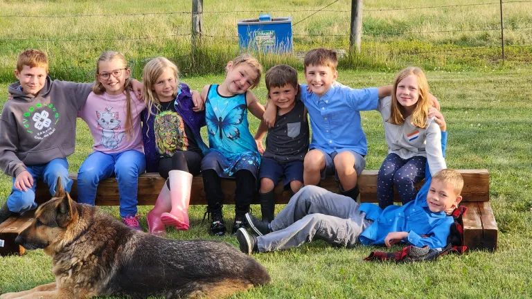 a group of children sitting outside with a dog