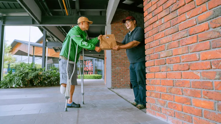 a man giving another man a paper bag