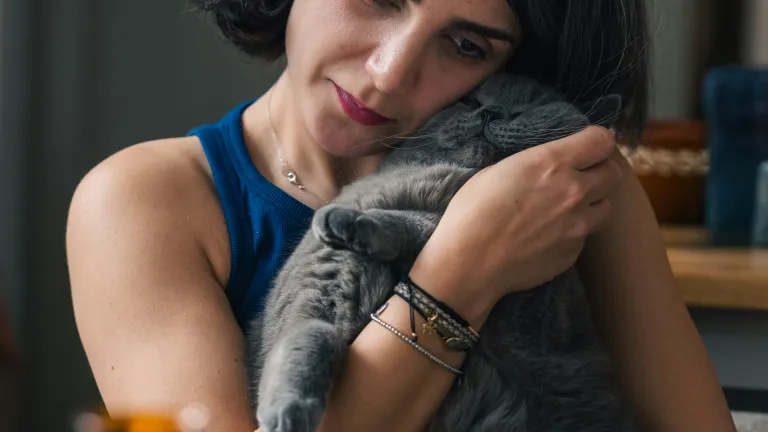 a sad woman hugging a gray cat